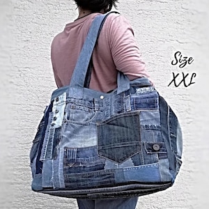 May include: XXL denim tote bag made from repurposed jeans. The bag features a patchwork design with various shades of blue denim, pockets, and a shoulder strap. The bag is large and spacious.