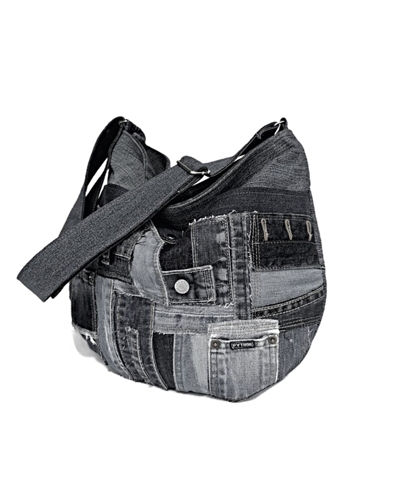 Puede incluir: Un bolso tote de mezclilla negro hecho de mezclilla reciclada con un dise&ntilde;o de patchwork. El bolso tiene una correa larga y un bolsillo peque&ntilde;o en la parte delantera.