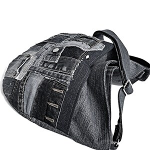 Puede incluir: Un bolso tote de lona negra con un dise&ntilde;o de patchwork. El bolso tiene una correa larga y un cierre de solapa.