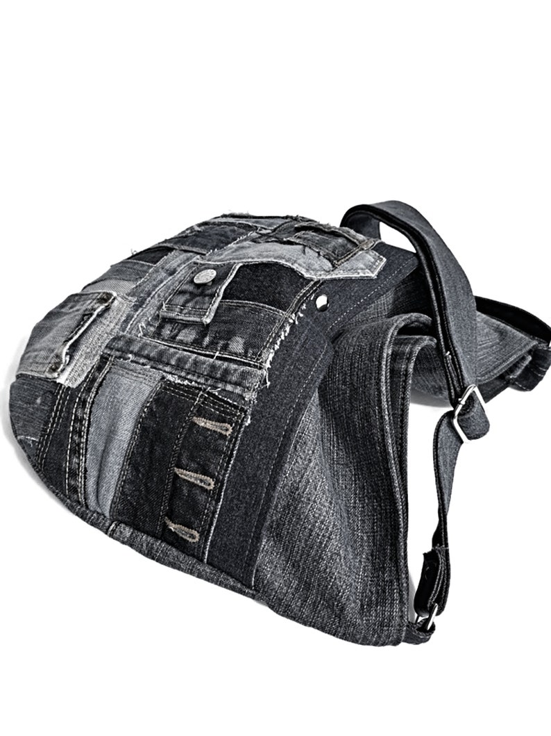 Puede incluir: Un bolso tote de lona negra con un dise&ntilde;o de patchwork. El bolso tiene una correa larga y un cierre de solapa.