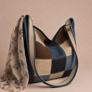 Könnte beinhalten: Eine Patchwork-Umhängetasche mit Jeans-, Beige- und braunen Quadraten. Die Tasche hat einen langen Riemen und einen floralen Schal. Das Design der Tasche ist eine Mischung aus Texturen und Farben.