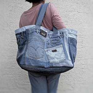 May include: A large tote bag made from repurposed denim. The bag has multiple pockets and is made from different shades of blue denim.