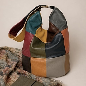 May include: A patchwork leather hobo bag in various colors, including teal, red, and tan. A matching olive green wallet and a set of keys with a brown leather fob are also visible. The bag has a black strap and a circular metal ring.