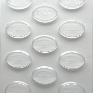 May include: A clear plastic mold with oval-shaped cavities. The word "Congratulations" is embossed in each oval, along with decorative flourishes. The mold also has the text "90-8073 CK" and "Approx. 33 Pieces per- Pcs/z".