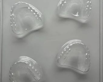 May include: Clear plastic mold with four taco-shaped cavities. The mold is designed for food use, with each cavity featuring a scalloped edge. The overall shape is rectangular, with the text "FOOD APP. MAT." visible.
