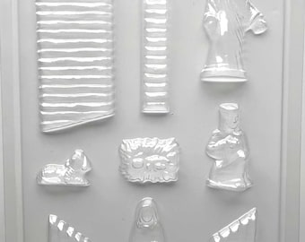 Könnte beinhalten: Eine transparente Kunststoffform mit verschiedenen religiösen Figuren und architektonischen Elementen. Die Form enthält eine Jesusfigur, ein Lamm und andere Figuren. Die Form dient zur Herstellung von Dekorationsartikeln.