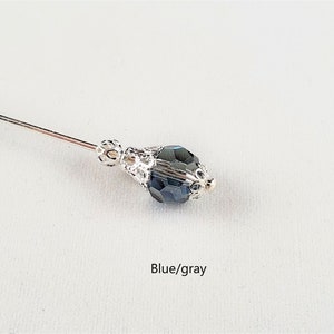 May include: A silver pin with a blue/gray faceted glass bead. The bead is set in a silver filigree design.