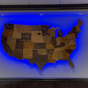May include: A wooden map of the United States with each state outlined in a different wood grain. The map is illuminated with blue LED lights.