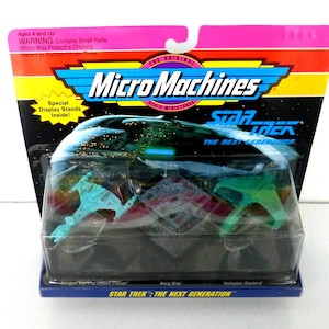 May include: Micro Machines Star Trek: The Next Generation miniature toy set. Includes Klingon Vor'cha Attack Cruiser, Borg Ship, and Romulan Warbird. The packaging features the Micro Machines logo and Star Trek branding.