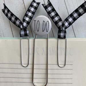 May include: Two silver binder clips with black and white checkered ribbon bows. The center clip has a white button with the text "TO DO" in black.