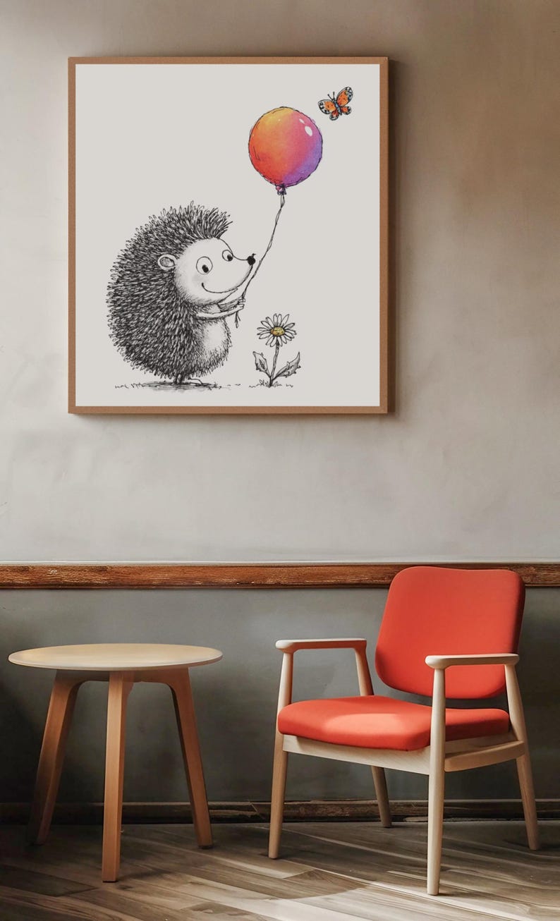May include: A framed illustration of a smiling hedgehog holding a colorful balloon. A butterfly hovers nearby. A daisy grows at the hedgehog's feet. The artwork is in a wooden frame, hanging on a neutral-colored wall. A round table and a red chair are in the foreground.