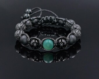 May include: A black beaded bracelet with a central green stone. The bracelet features a macrame design with black beads and a reflective surface. The bracelet is a stylish accessory.