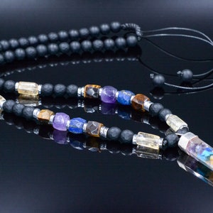 May include: A black beaded necklace with a variety of colorful gemstones and a crystal pendant. The necklace features a mix of black matte beads, clear and colorful gemstones, and a long, multi-colored crystal pendant.