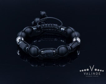 May include: Black onyx beaded bracelet with silver accents and a black cord. The bracelet is tied with a knot and has a silver clasp.