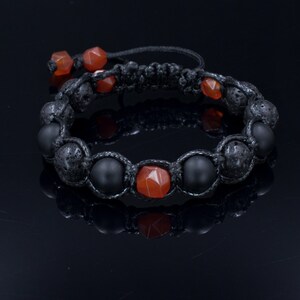 Puede incluir: Pulsera de piedra de lava negra y piedra de cornalina con cordón negro. La pulsera está atada con un nudo macramé.