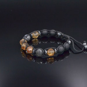 Peut inclure: Un bracelet en perles noires avec des perles de pierres pr&eacute;cieuses brunes et grises. Le bracelet est dot&eacute; d'un cordon noir avec un n&oelig;ud coulissant pour ajuster la taille.
