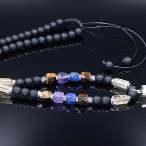 May include: Black beaded necklace with colorful gemstone accents and a clear crystal pendant with rainbow-colored layers. The necklace features a black cord and a silver-colored metal clasp.