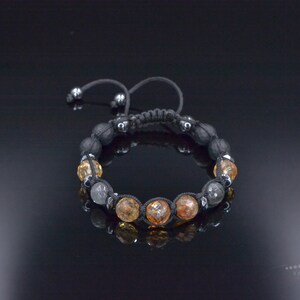 Peut inclure: Un bracelet en cordon noir avec des perles grises et ambr&eacute;es. Le bracelet est nou&eacute; et poss&egrave;de une perle coulissante pour ajuster la taille.