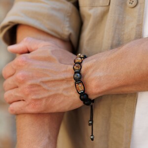 Peut inclure: Un bracelet en perles noires avec des perles de pierres pr&eacute;cieuses brunes et grises. Le bracelet a un cordon noir avec des perles argent&eacute;es.