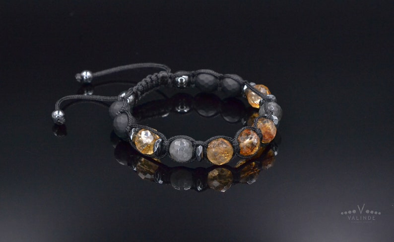 Peut inclure: Un bracelet en cordon noir avec des perles de pierres pr&eacute;cieuses brunes et grises. Le bracelet a une fermeture &agrave; n&oelig;ud coulissant.