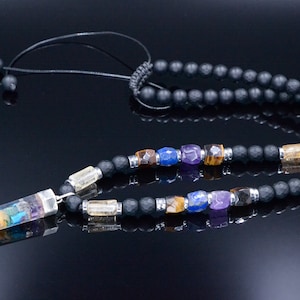 May include: A black beaded necklace with a pendant featuring a rainbow-colored crystal. The necklace includes various colorful gemstones and is designed with a black cord and adjustable knot.