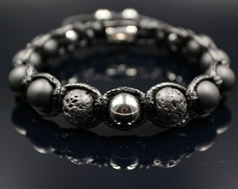 Könnte beinhalten: Schwarzes Perlenarmband mit Lavasteinen und Metallperlen. Das Armband ist aus schwarzem Band gefertigt und hat einen silbernen Verschluss.