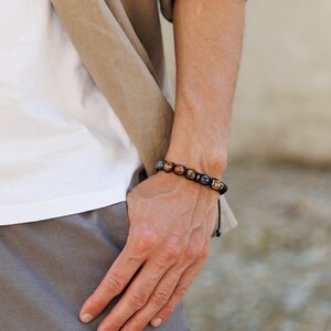 Peut inclure: Un bracelet en cordon noir avec des perles de pierres pr&eacute;cieuses brunes et grises.