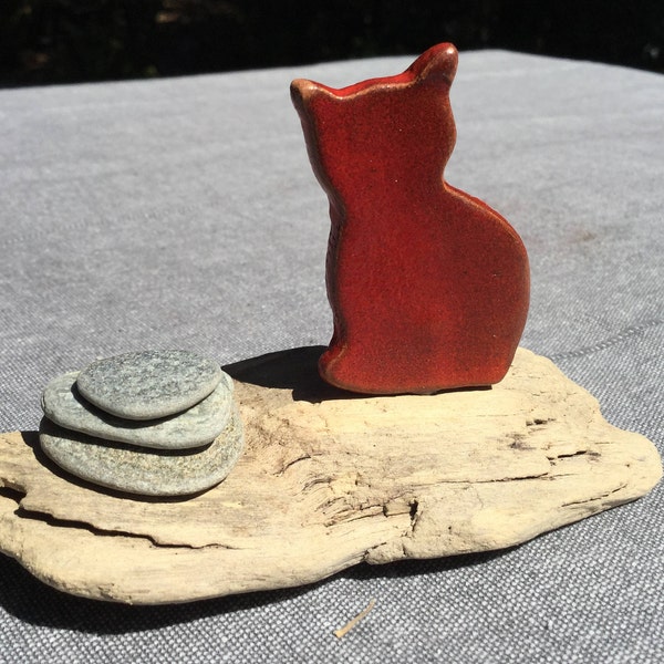 Petit chat en céramique sur bois flotté et petits cailloux