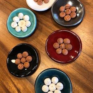 Peut inclure: Six petites assiettes en céramique, chacune avec un glaçage de couleur différente, contiennent de petits ornements en argile ronds avec différentes textures et motifs. Les ornements sont disposés en cercle sur chaque assiette.