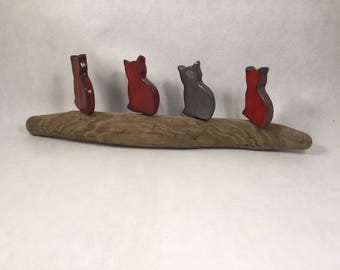4 small enameled cats sitting on driftwood