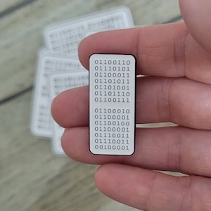 May include: A white rectangular pin with black text. The text is a series of binary code: 01100110 01110101 01100011 01101001 01101111 01100110 01100101 01110011 01100010 01100001 01100000 01100001 01100100 01100101 01110011 01100001 00100000 01100010 01100001 01100000 01100001 01100100 01100101 01110011 01100001
