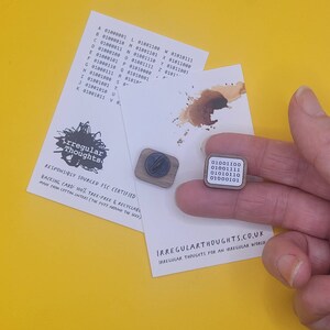 May include: Two wooden pins featuring a coffee bean design and a binary code design. The pins are displayed on a yellow surface with a white card that reads "Irregular Thoughts" and "Responsibly Sourced FSC Certified".