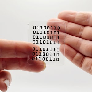 May include: A clear plastic sticker with a series of binary code printed on it. The code reads: 01100110 01110101 01100011 01101011 01101111 01100110 01100110