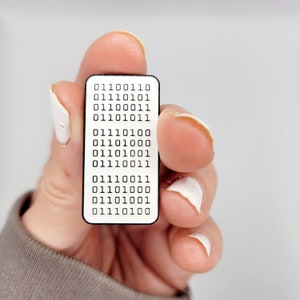 Peut inclure: Une épingle en émail blanc avec une bordure noire et du texte noir. Le texte est "01110011 01111010 01110001 01110111 01110101 01111000 01110100 01110001 01110011 01110011 01110100 01110000 01110101 01110100".