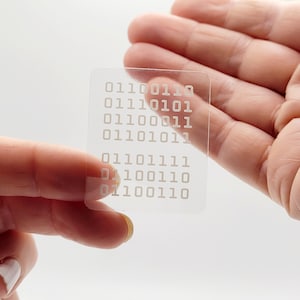 May include: A clear plastic sheet with a grid of white binary code printed on it. The code includes the numbers 01100110, 01110101, 01100011, 01101011, 01101111, 01100110, 01100110, and 01100110.