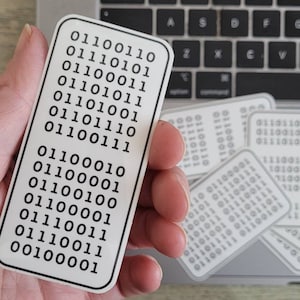 May include: A white sticker with black text that reads "01100110 01100010 01100001 01101110 01101001 01101011 01100011 01110101 01100110 01100001 01100001 01110011 01110011 00100001".