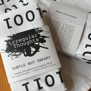 May include: White tote bag with black binary code printed on it. The bag has a black tag attached to it that says "Irregular Thoughts" and "Subtle But Sweary". The tag also includes the website address "IrregularThoughts.etsy.com".