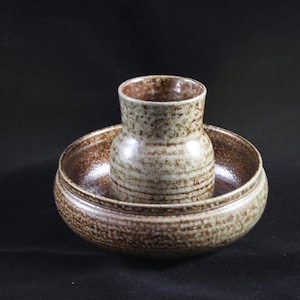 Puede incluir: Un cuenco de cerámica moteado en marrón y blanco con un jarrón de cerámica moteado en marrón y blanco más pequeño en su interior.