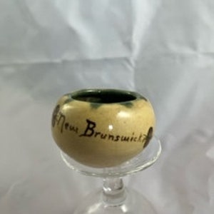 Puede incluir: Un pequeño plato redondo de cerámica con un esmalte verde y una inscripción pintada a mano que dice "Nuevo Brunswick".