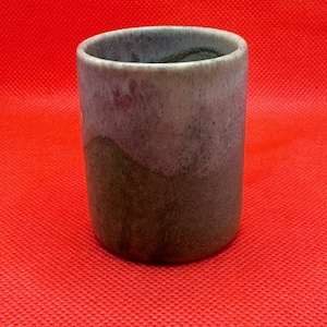 Puede incluir: Una taza de cerámica con un esmalte gris claro y morado en la mitad superior y un esmalte verde oscuro y marrón en la mitad inferior.