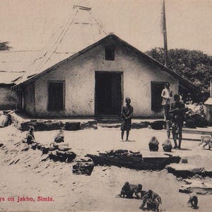 May include: Vintage black and white postcard featuring a building with a thatched roof and several people standing outside. Monkeys are scattered around the yard. The text at the bottom reads "Monkeys on Jakho, Simla."