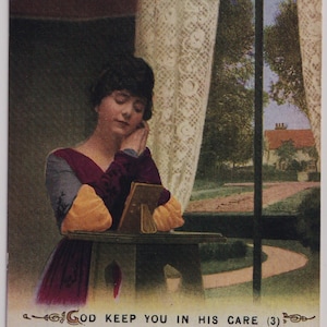 May include: Vintage postcard featuring a woman in a burgundy dress, resting her head on her hands. The image includes text with a poem and the phrase "GOD KEEP YOU IN HIS CARE." A window with lace curtains and a view of a house and trees is in the background.