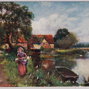 以下が含まれることがあります： 「The Farm by the River」と題されたヴィンテージの絵葉書のイラスト。紫色のドレスを着た人物が、小さなボート、大きな木、赤い屋根の農家がある川岸に立っており、背景には曇り空が描かれています。