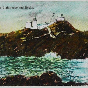 K&ouml;nnte beinhalten: Vintage Postkarte mit dem Leuchtturm und den Felsen von The Casquets. Das Bild zeigt einen Leuchtturmkomplex auf einer felsigen Insel, mit einem Weg, der zu den Geb&auml;uden f&uuml;hrt. Das Meer umgibt die Insel, mit Wellen, die gegen die Felsen schlagen. Der Himmel ist eine Mischung aus Blau und Wei&szlig;.