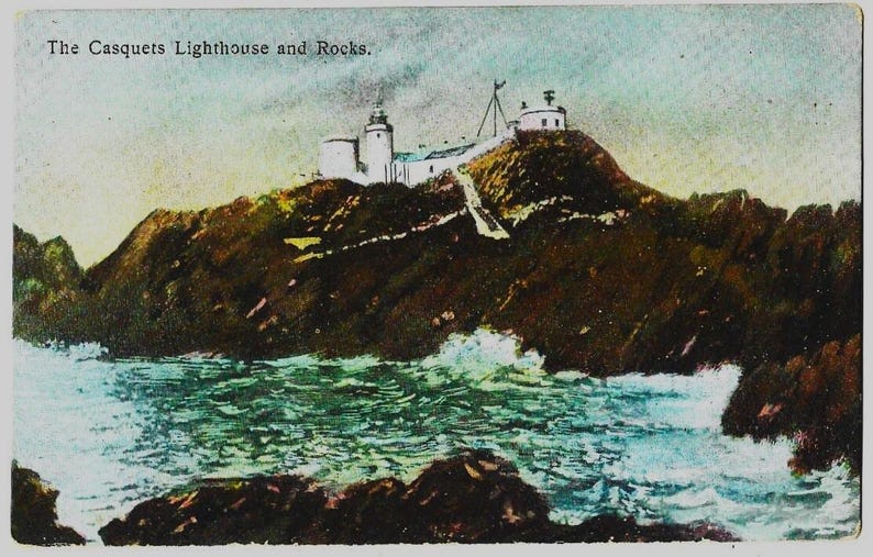 K&ouml;nnte beinhalten: Vintage Postkarte mit dem Leuchtturm und den Felsen von The Casquets. Das Bild zeigt einen Leuchtturmkomplex auf einer felsigen Insel, mit einem Weg, der zu den Geb&auml;uden f&uuml;hrt. Das Meer umgibt die Insel, mit Wellen, die gegen die Felsen schlagen. Der Himmel ist eine Mischung aus Blau und Wei&szlig;.