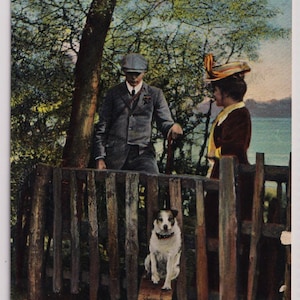 May include: A vintage postcard showing a man and woman by a wooden fence, with a dog sitting on a small bench. The background includes trees and water. The text "THE TRYSTING PLACE" is visible at the bottom of the image.