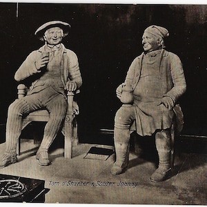 May include: A monochrome postcard showing two seated sculptures of men in period attire. One holds a glass, the other a jug. The text "Tam o'Shanter & Souter Johnny" is at the bottom. The sculptures are seated on chairs, and the image has a vintage aesthetic.