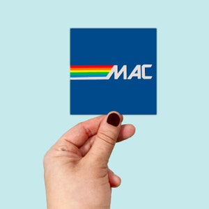 Könnte beinhalten: Ein blauer quadratischer Aufkleber mit einem Regenbogenstreifen und dem Wort "MAC" in weißen Buchstaben.