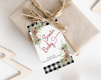 Peut inclure: Une étiquette cadeau blanche avec une bordure en vichy noir et blanc. L'étiquette présente une illustration aquarelle de branches de pin, de pommes de pin et de baies rouges. Le texte "Santa Baby" est écrit en cursive rouge. Le texte "Thank You! From Sarah & Baby Rhett" est écrit en noir sous l'illustration.