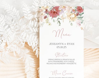 Op de afbeelding: Een huwelijksmenukaart met bloemillustraties. Het menu bevat een voorgerecht, een hoofdgerecht en een dessert. De tekst luidt "Menu", "Jessamyn & Ryan", "05.18.25", "Voorgerecht", "Salade van verse spinazie en groene bladeren met aardbeien, feta, pecannoten en frambozenvinaigrette", "Hoofdgerecht", "Geroosterde kipfilet geserveerd op een risotto met champignons en tijm, met een romige kippenjus", "Dessert", "Warme toffee-pudding met donkere chocoladesaus".